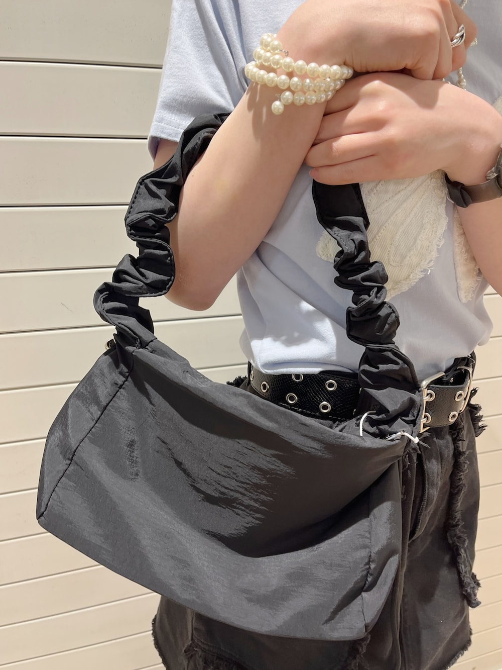 ブラック系のショルダーバッグ、ブラック系のスカート、ブルー系のTシャツ/カットソーを着用したレディースの春コーディネートの7枚目の写真