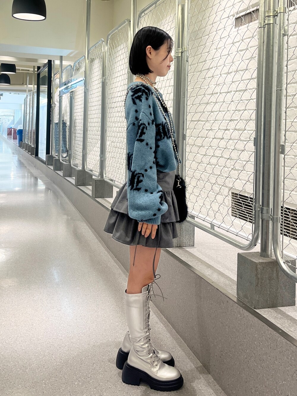 シルバー系のブーツ、ブルー系のカーディガン/ボレロ、ブラック系のハンドバッグを着用したレディースの夏コーディネートの3枚目の写真