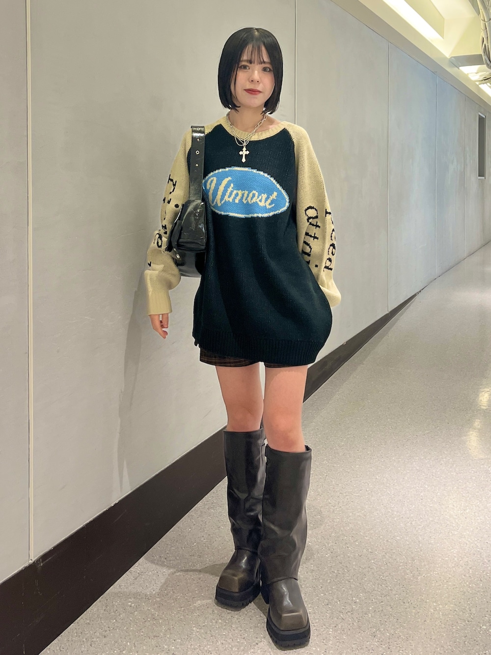 ブラック系のニット/セーター、ブラウン系のスカート、ブラック系のショルダーバッグを着用したレディースの秋コーディネートの2枚目の写真