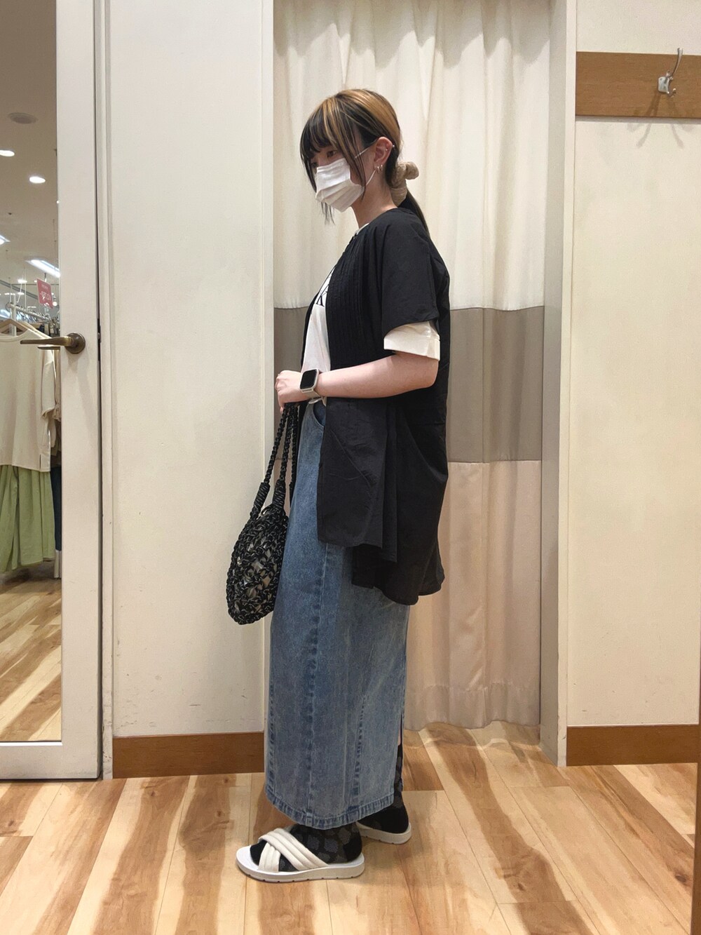 ブラック系のシャツ/ブラウス、ブラック系のハンドバッグ、ブルー系のデニムスカートを着用したレディースの春コーディネートの2枚目の写真