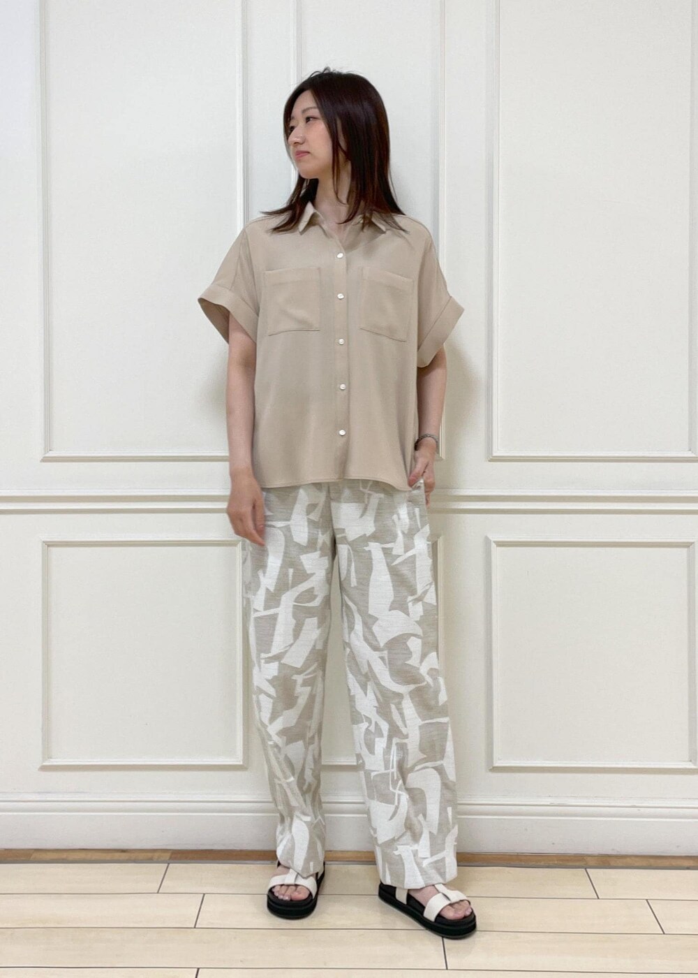 ブラック系のショルダーバッグ、ホワイト系のサンダル、ベージュ系のシャツ/ブラウスを着用したレディースの春コーディネートの6枚目の写真