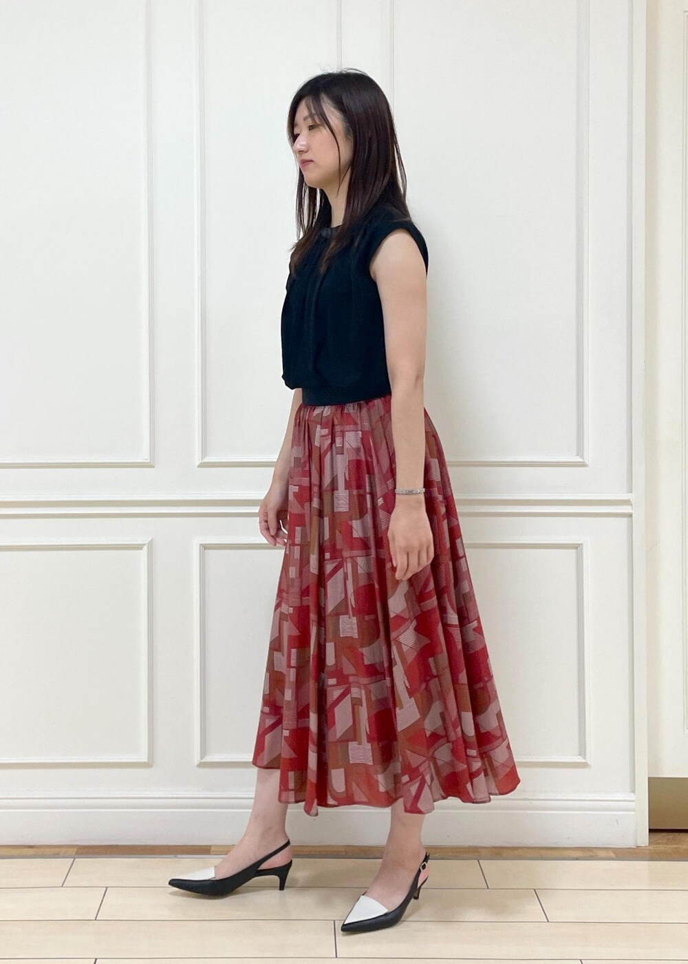 ブラック系のパンプス、レッド系のスカート、ブラック系のTシャツ/カットソーを着用したレディースの夏コーディネートの2枚目の写真