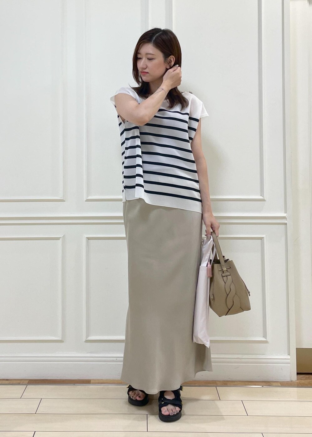 ベージュ系のショルダーバッグ、ベージュ系のスカート、ブルー系のシャツ/ブラウスを着用したレディースの夏コーディネートの2枚目の写真