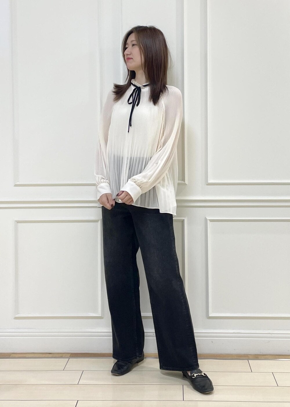 ホワイト系のショルダーバッグ、ブラック系のデニムパンツを着用したレディースの秋コーディネートの2枚目の写真
