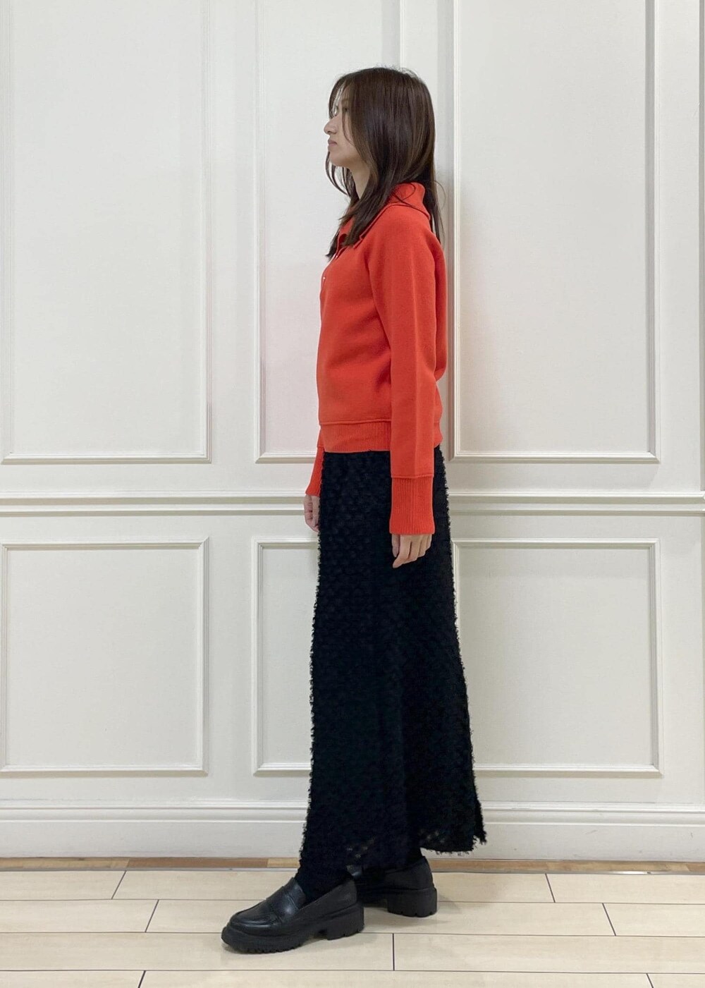 レッド系のニット/セーター、ブラック系のスカート、ベージュ系のハンドバッグを着用したレディースの秋コーディネートの5枚目の写真