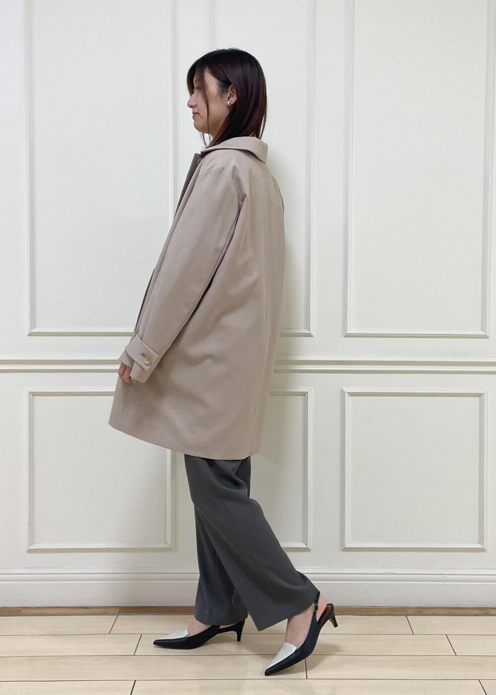 ブラック系のトートバッグ、ベージュ系のステンカラーコート、ブラック系のパンプスを着用したレディースの春コーディネートの2枚目の写真
