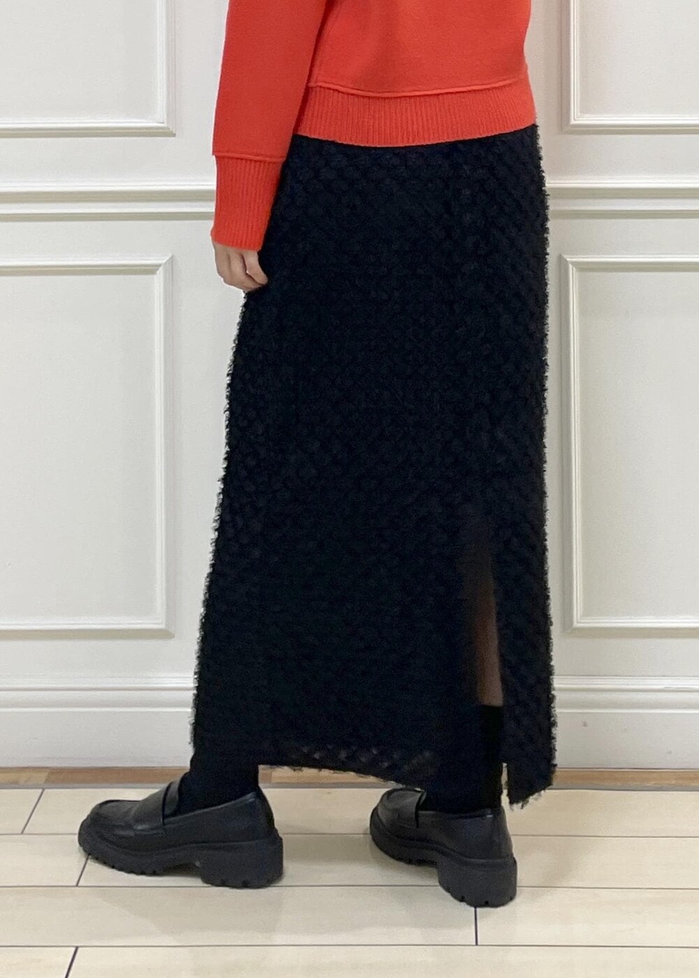 レッド系のニット/セーター、ブラック系のスカート、ベージュ系のハンドバッグを着用したレディースの秋コーディネートの7枚目の写真