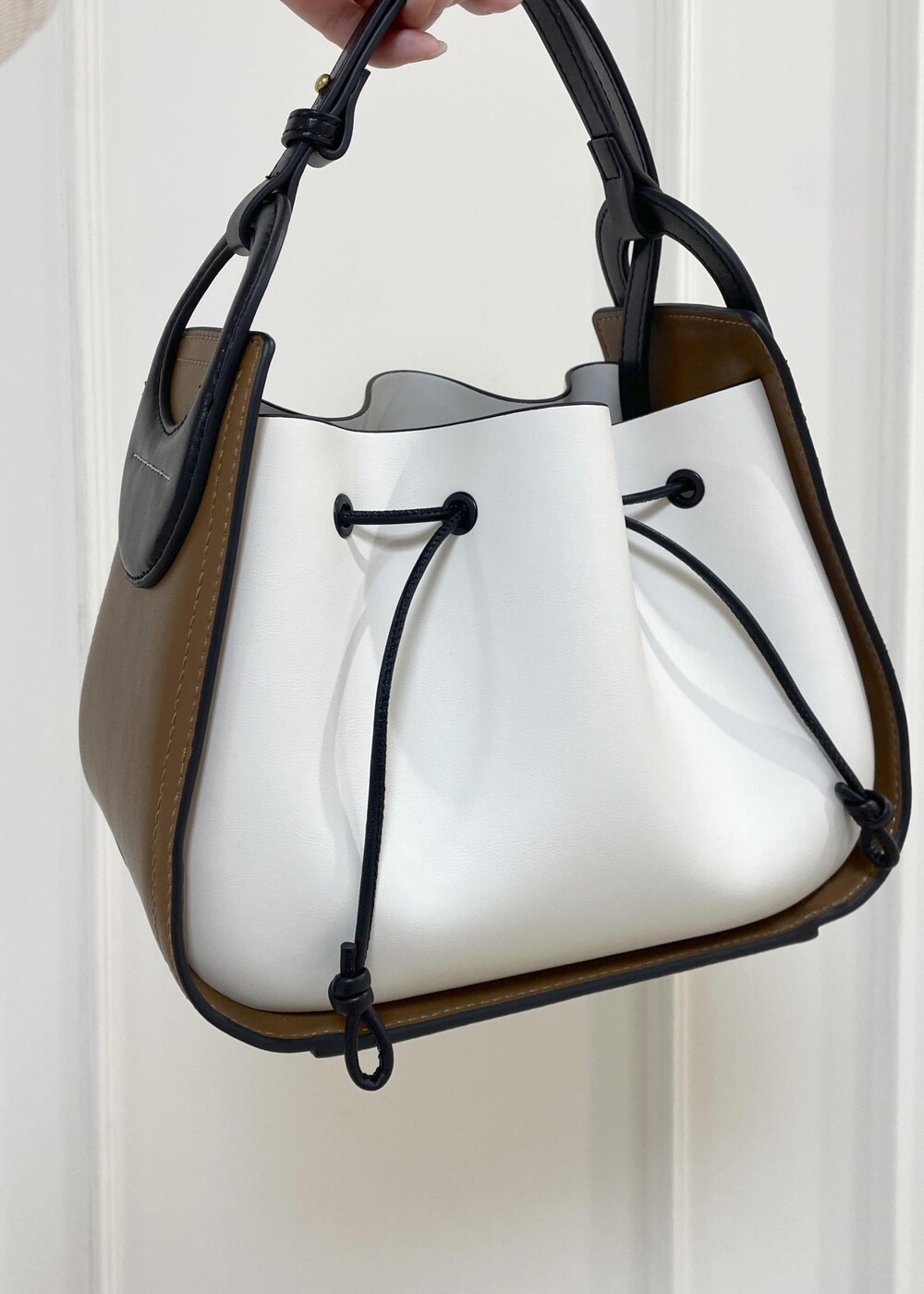 ホワイト系のハンドバッグ、ブラック系のローファー、ホワイト系のニット/セーターを着用したレディースの秋コーディネートの7枚目の写真