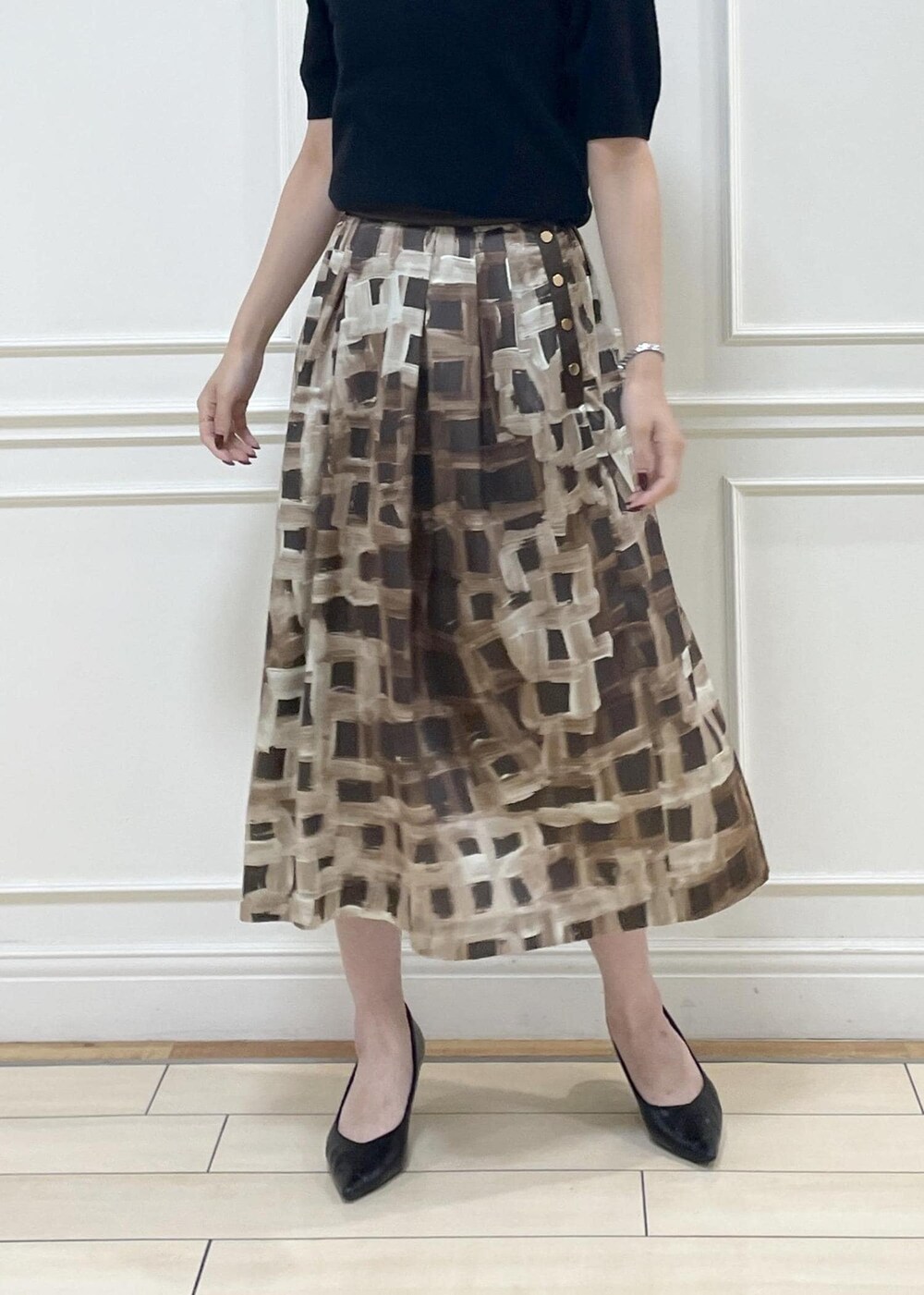 グレー系のハンドバッグ、ブラウン系のスカート、ブラック系のニット/セーターを着用したレディースの秋コーディネートの5枚目の写真