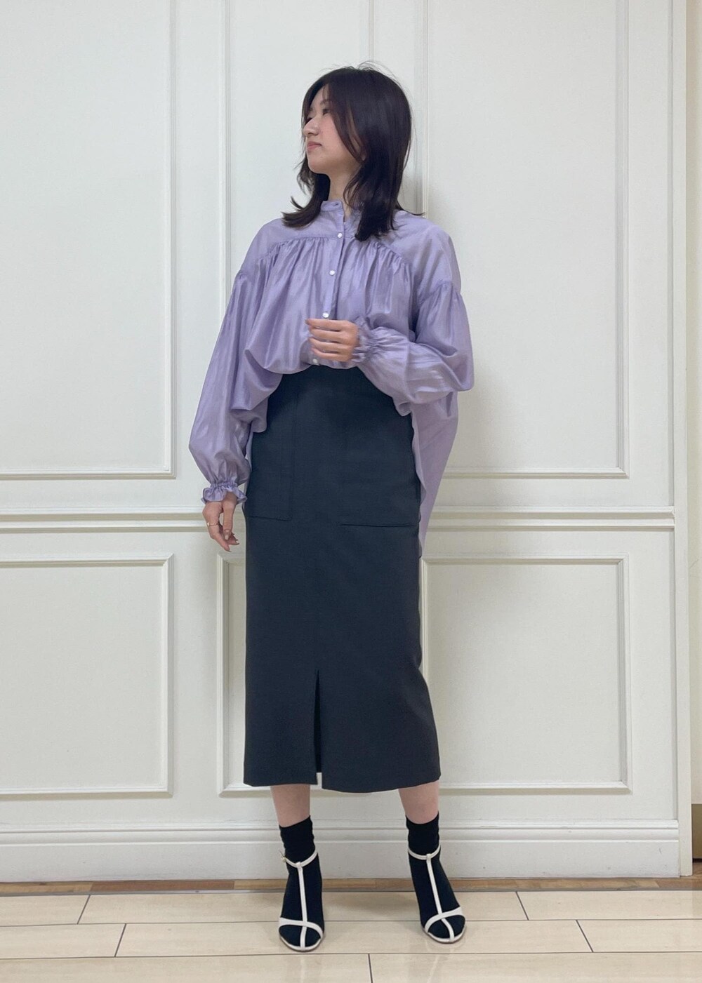 ホワイト系のハンドバッグ、ブラック系のスカート、ホワイト系のサンダルを着用したレディースの春コーディネートの5枚目の写真