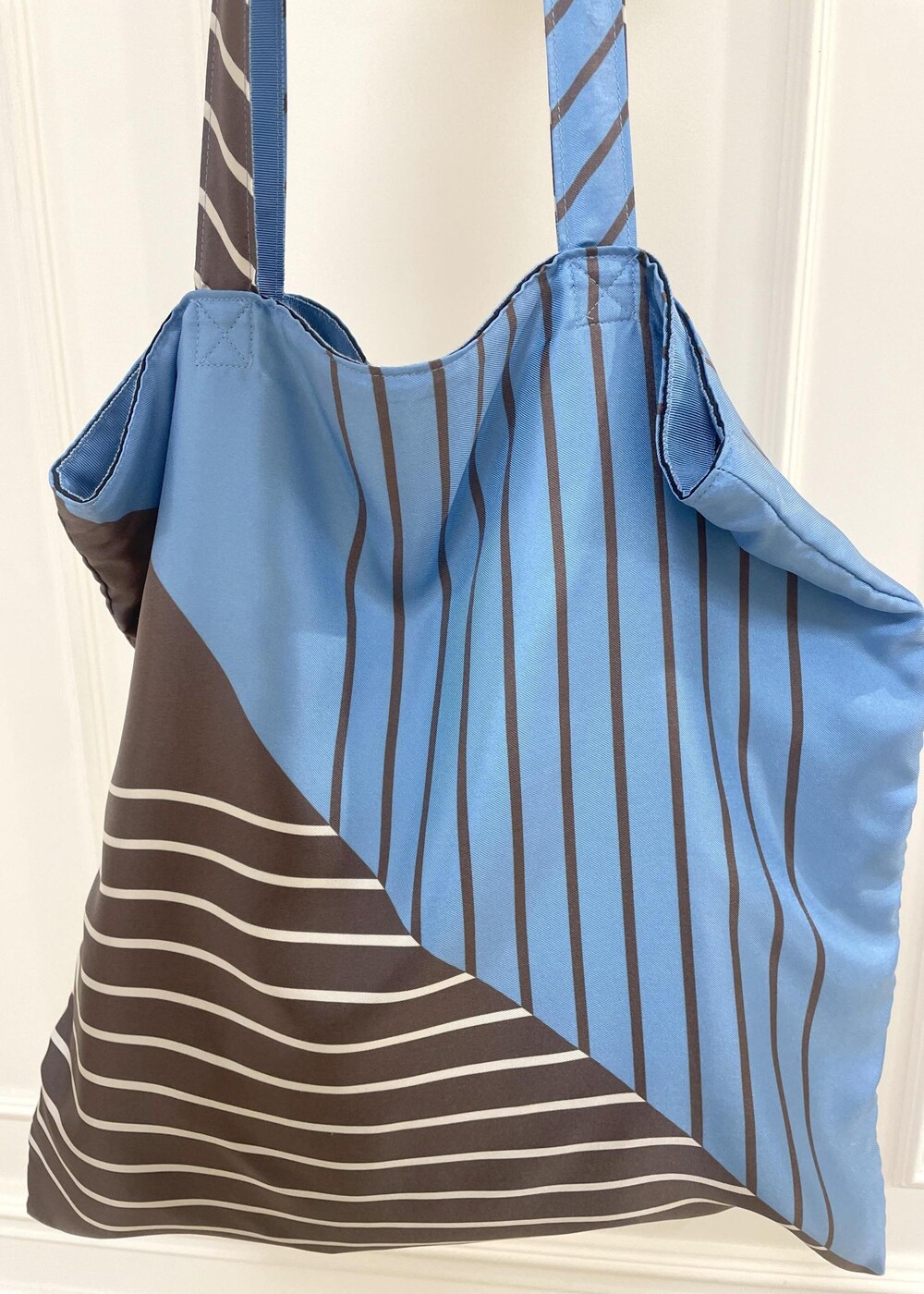 ブルー系のトートバッグ、グレー系のスカート、ベージュ系のスウェットを着用したレディースの秋コーディネートの7枚目の写真