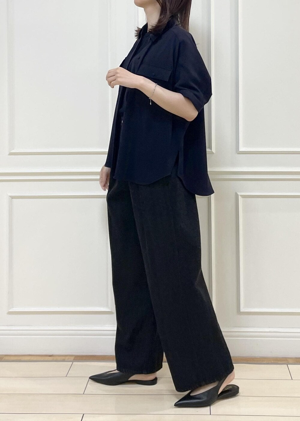 ブラック系のデニムパンツ、ベージュ系のショルダーバッグ、ブルー系のニット/セーターを着用したレディースの春コーディネートの2枚目の写真