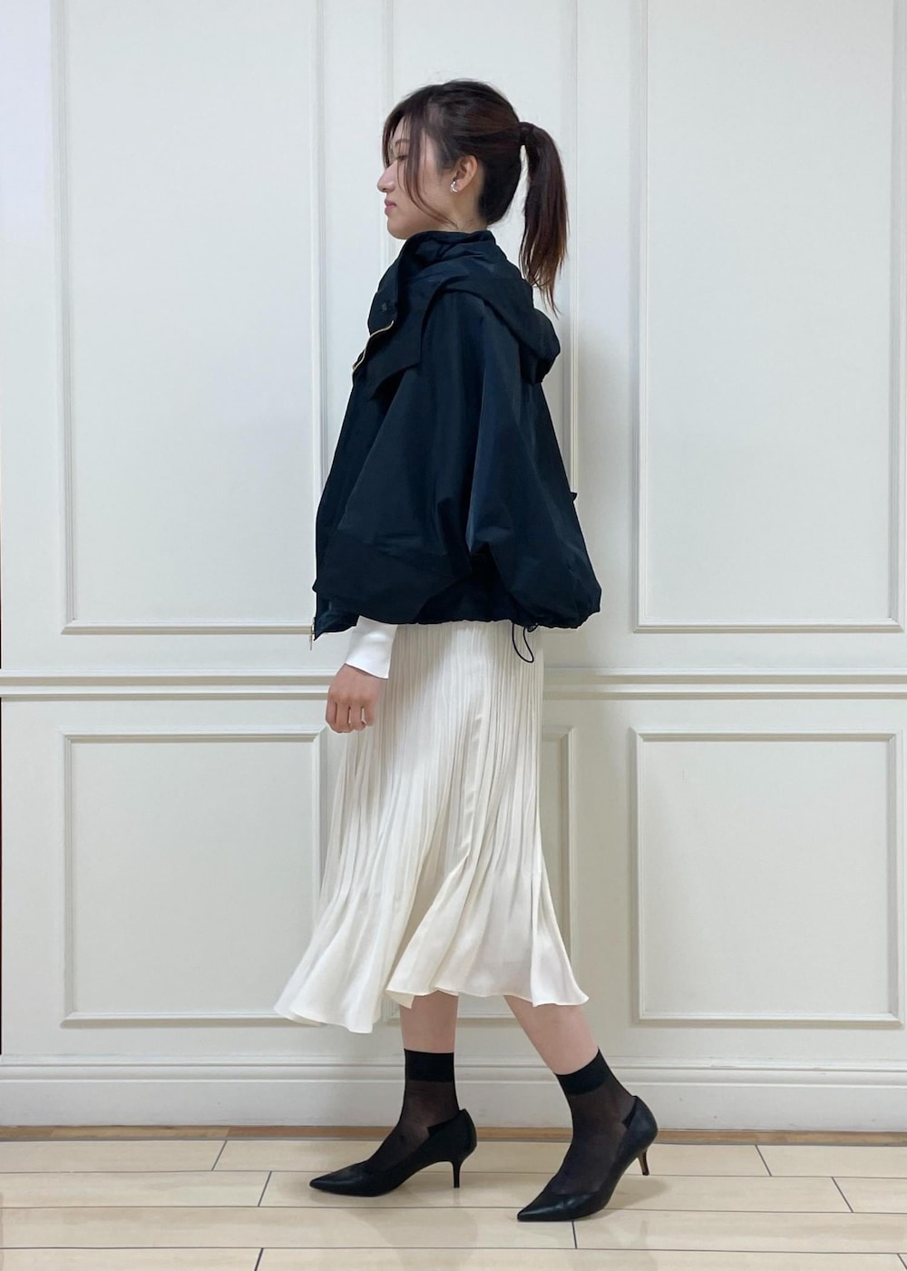 ブラック系のパンプス、ホワイト系のスカート、ブラック系のハンドバッグを着用したレディースの春コーディネートの3枚目の写真