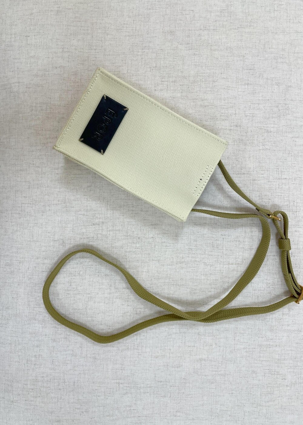 ブラック系のデニムパンツ、ベージュ系のショルダーバッグ、ブルー系のニット/セーターを着用したレディースの春コーディネートの8枚目の写真