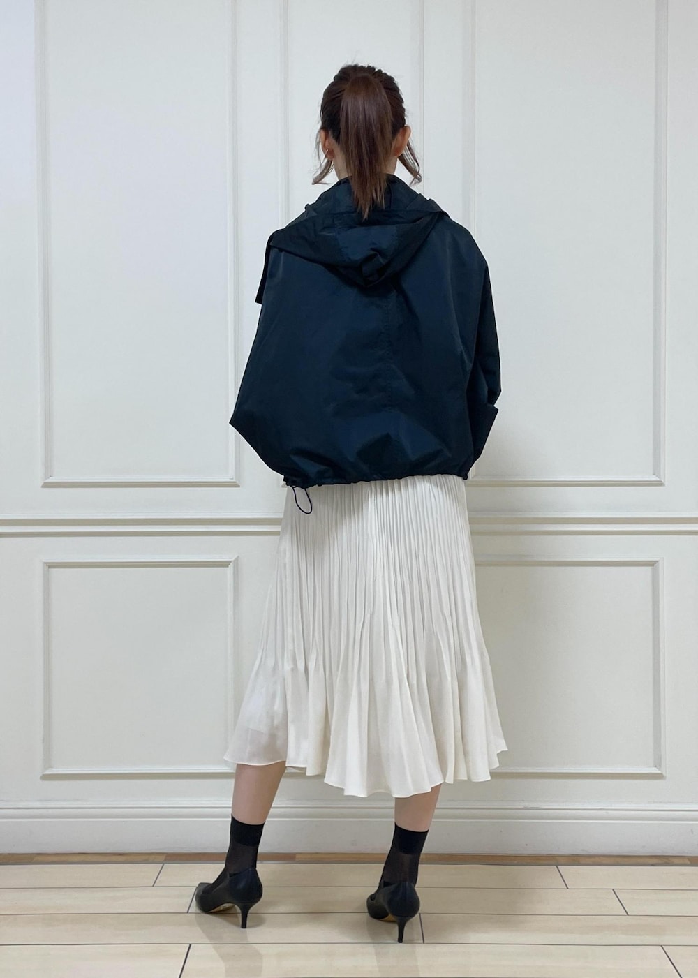 ブラック系のパンプス、ホワイト系のスカート、ブラック系のハンドバッグを着用したレディースの春コーディネートの4枚目の写真
