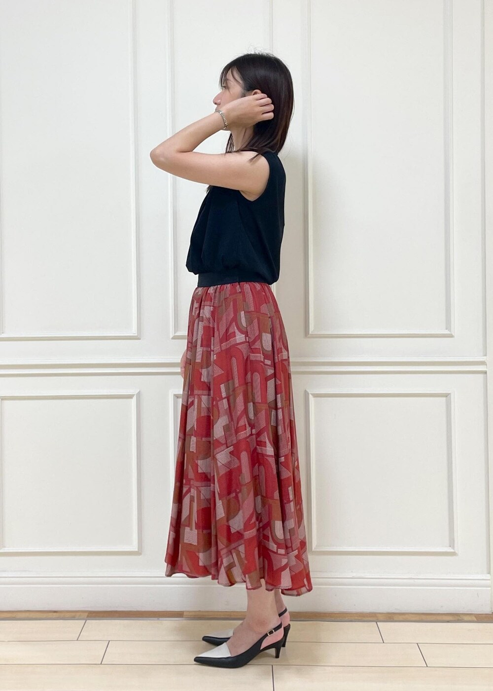 ブラック系のパンプス、レッド系のスカート、ブラック系のTシャツ/カットソーを着用したレディースの夏コーディネートの3枚目の写真