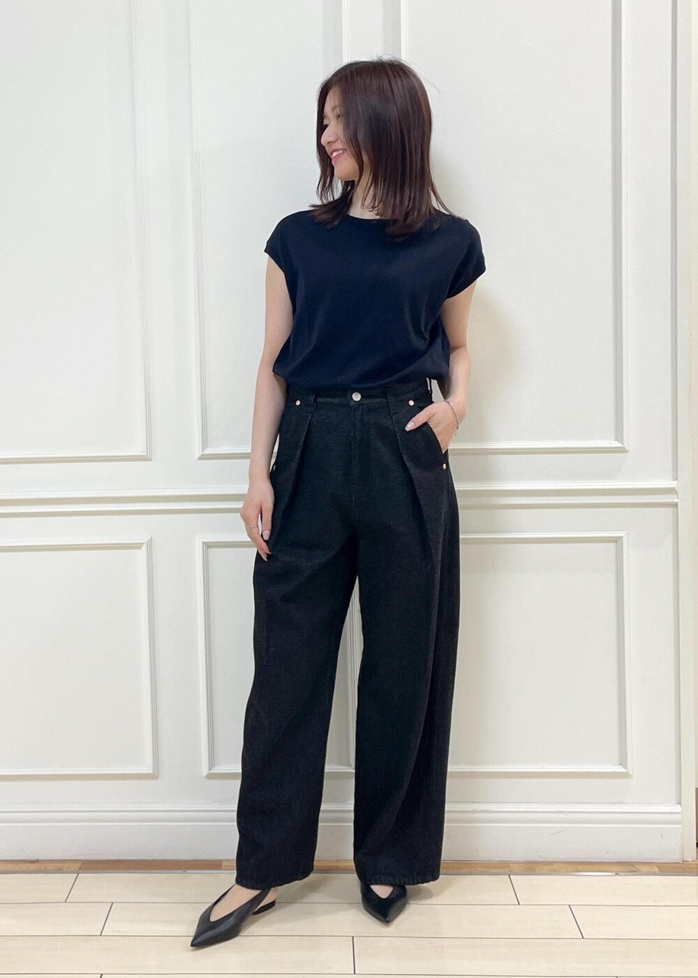 ブラック系のデニムパンツ、ベージュ系のショルダーバッグ、ブルー系のニット/セーターを着用したレディースの春コーディネートの4枚目の写真