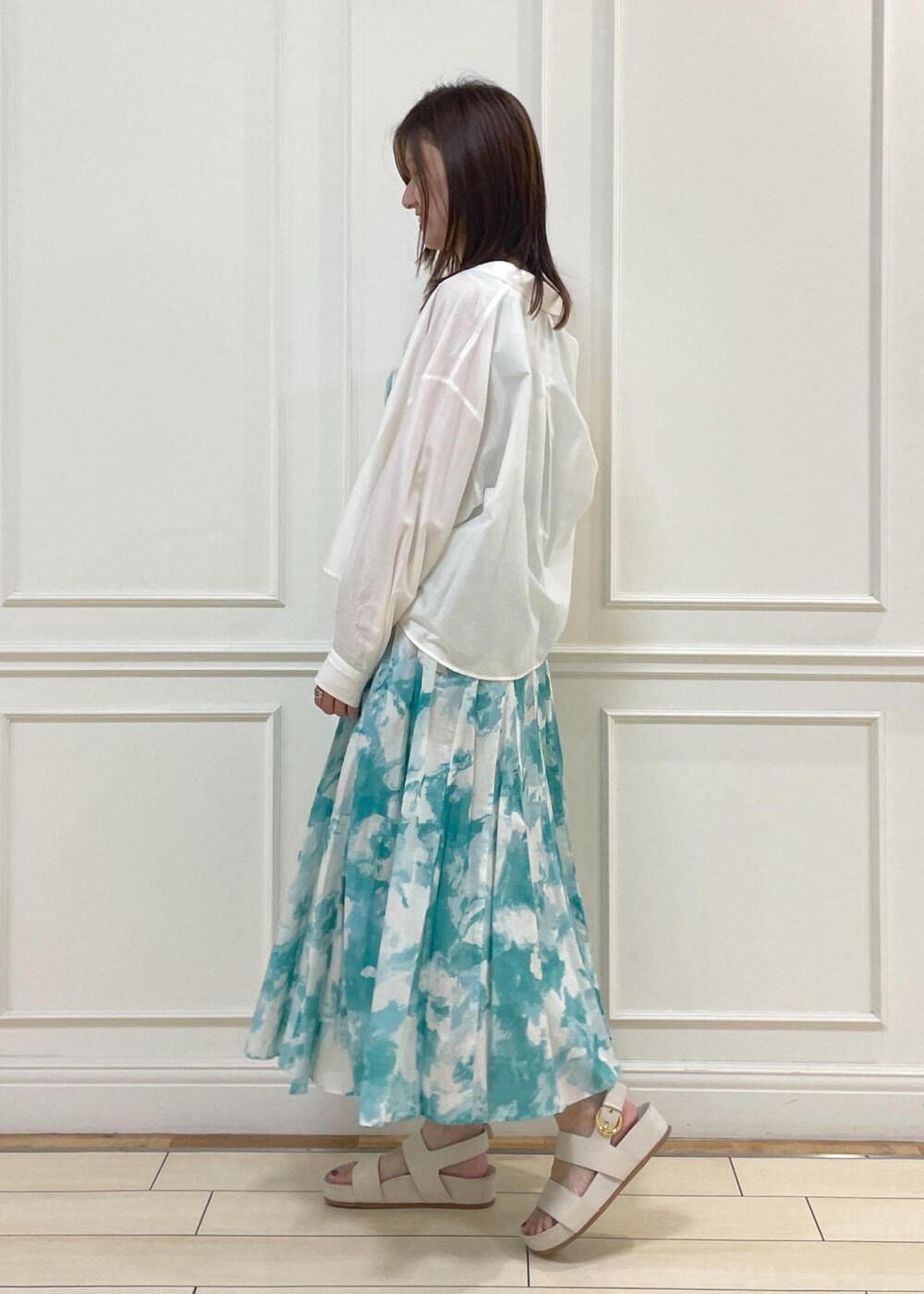 ベージュ系のショルダーバッグ、ホワイト系のシャツ/ブラウス、ベージュ系のサンダルを着用したレディースの夏コーディネートの2枚目の写真