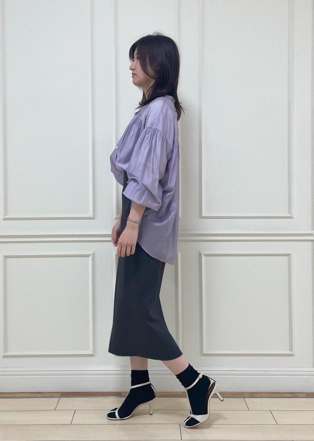 ホワイト系のハンドバッグ、ブラック系のスカート、ホワイト系のサンダルを着用したレディースの春コーディネートの3枚目の写真