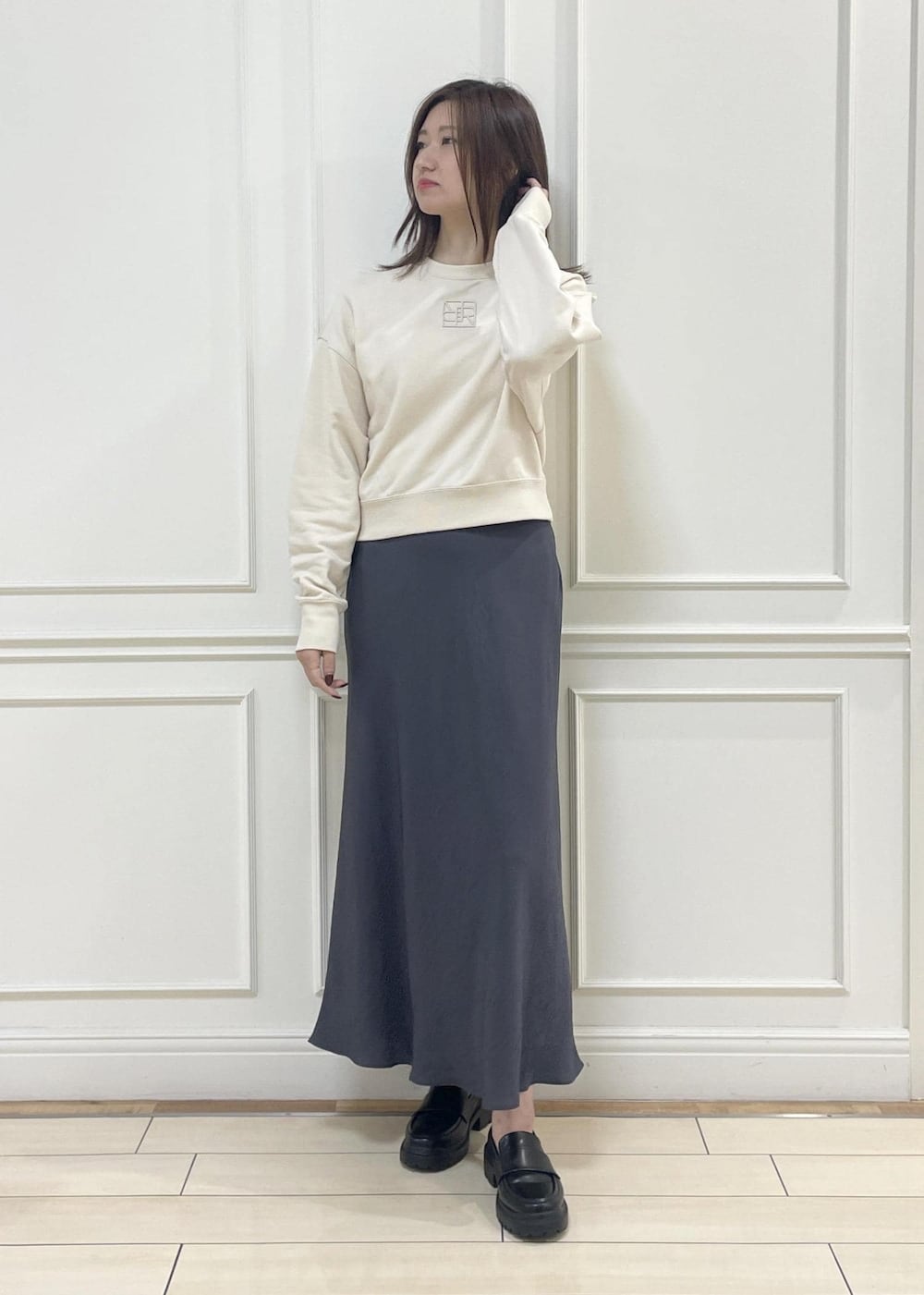 ブルー系のトートバッグ、グレー系のスカート、ベージュ系のスウェットを着用したレディースの秋コーディネートの3枚目の写真