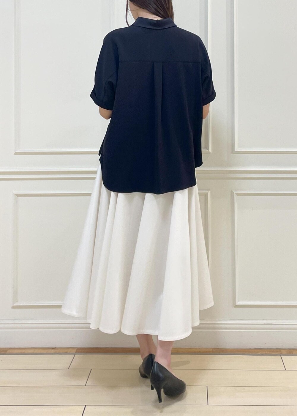 ブラック系のハンドバッグ、ホワイト系のスカート、ホワイト系のニット/セーターを着用したレディースの春コーディネートの4枚目の写真