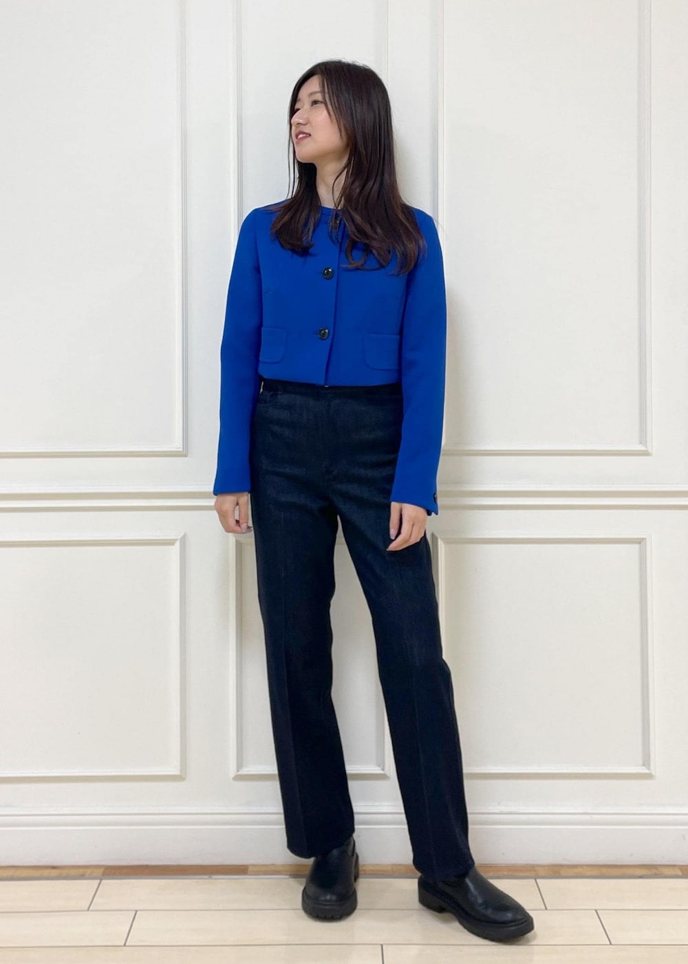 ブルー系のデニムパンツ、ホワイト系のハンドバッグ、ブルー系のノーカラージャケットを着用したレディースの秋コーディネートの2枚目の写真