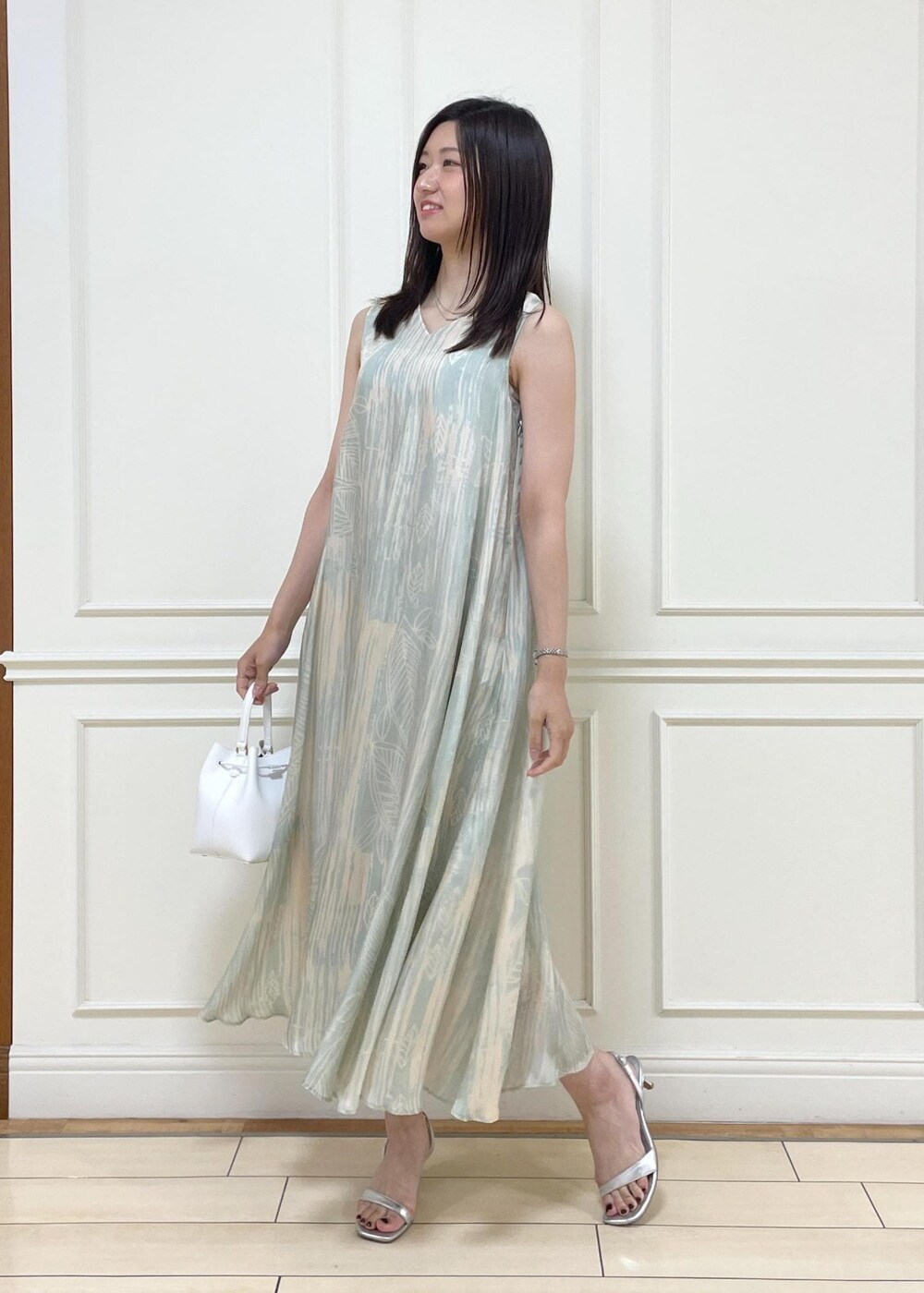ホワイト系のハンドバッグ、シルバー系のサンダル、グリーン系のワンピースを着用したレディースの夏コーディネートの2枚目の写真