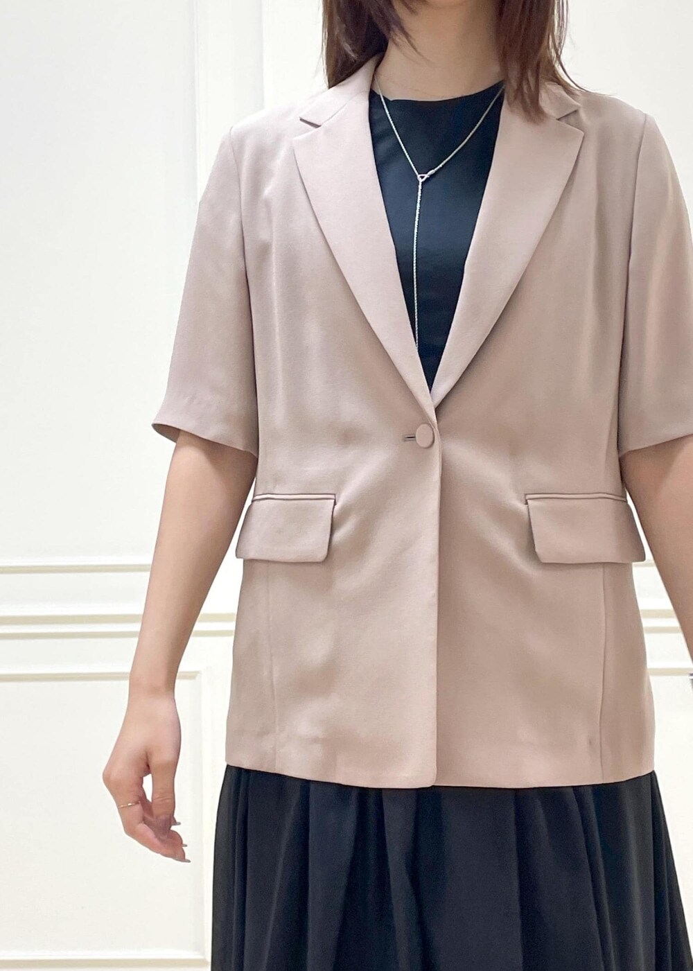 ブラウン系のトートバッグ、ベージュ系のテーラードジャケット、ブラック系のスカートを着用したレディースの夏コーディネートの2枚目の写真