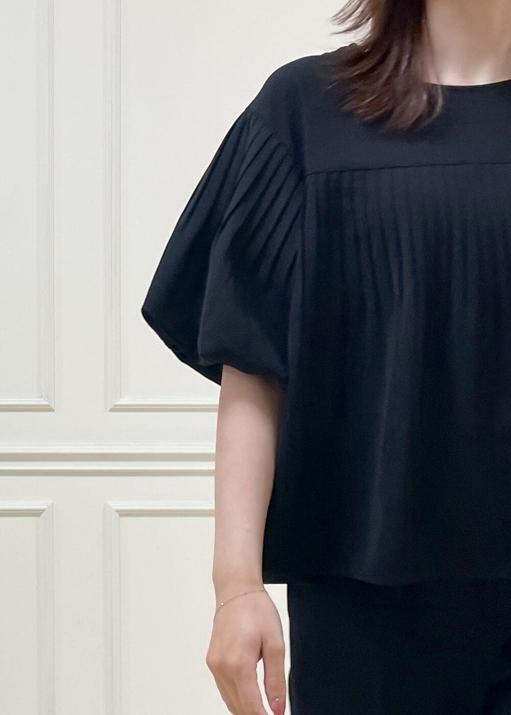 ブラック系のハンドバッグ、ブラック系のパンプス、ブラック系のベストを着用したレディースの春コーディネートの6枚目の写真