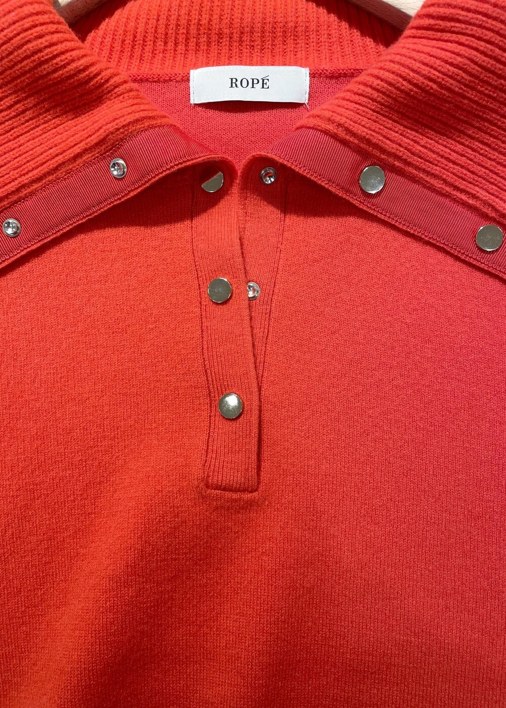 レッド系のニット/セーター、ブラック系のスカート、ベージュ系のハンドバッグを着用したレディースの秋コーディネートの4枚目の写真