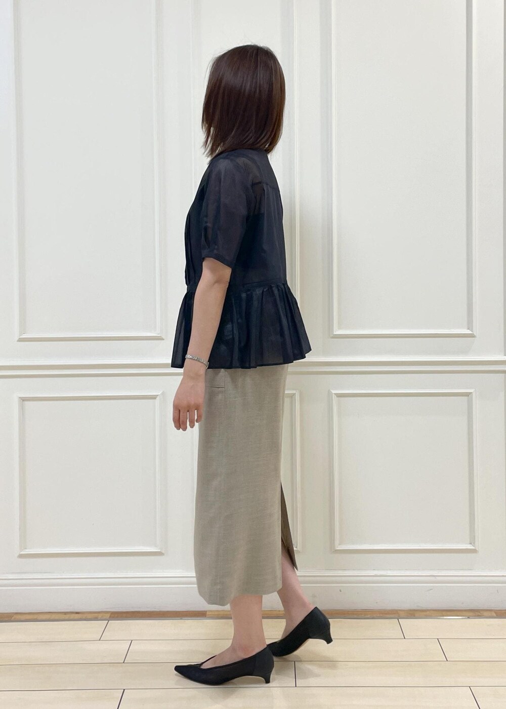 ブラック系のハンドバッグ、ベージュ系のスカート、ブルー系のシャツ/ブラウスを着用したレディースの夏コーディネートの2枚目の写真