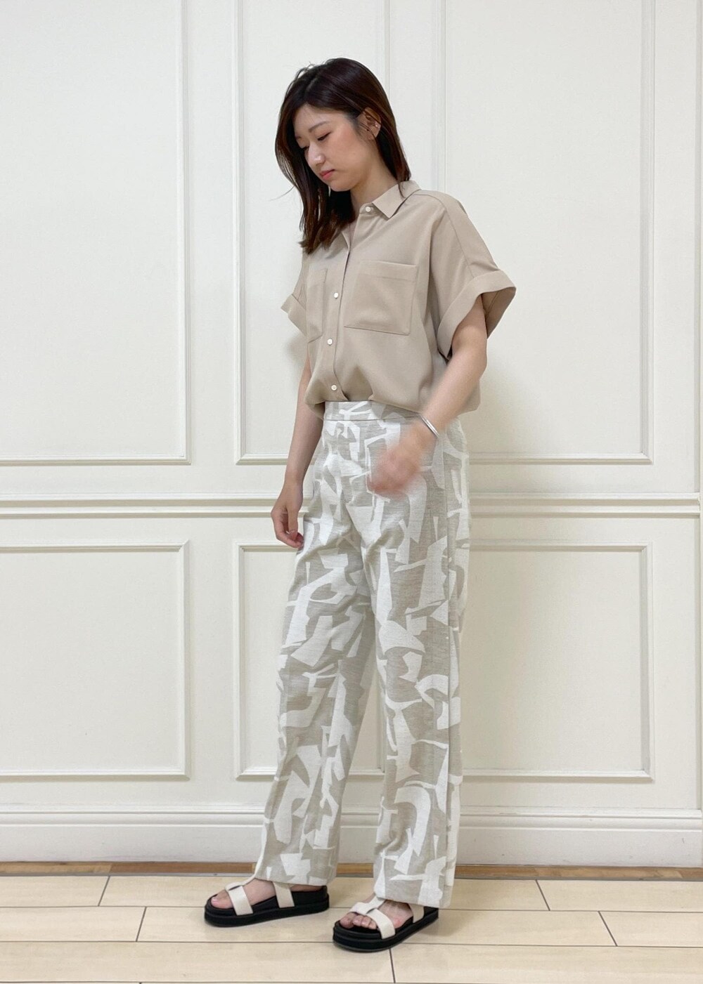 ブラック系のショルダーバッグ、ホワイト系のサンダル、ベージュ系のシャツ/ブラウスを着用したレディースの春コーディネートの2枚目の写真