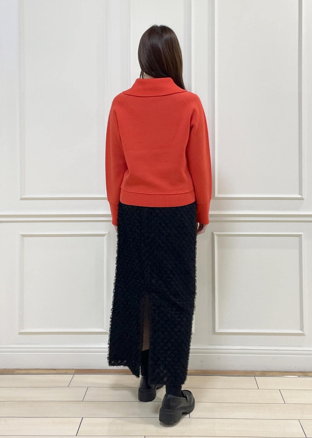 レッド系のニット/セーター、ブラック系のスカート、ベージュ系のハンドバッグを着用したレディースの秋コーディネートの6枚目の写真