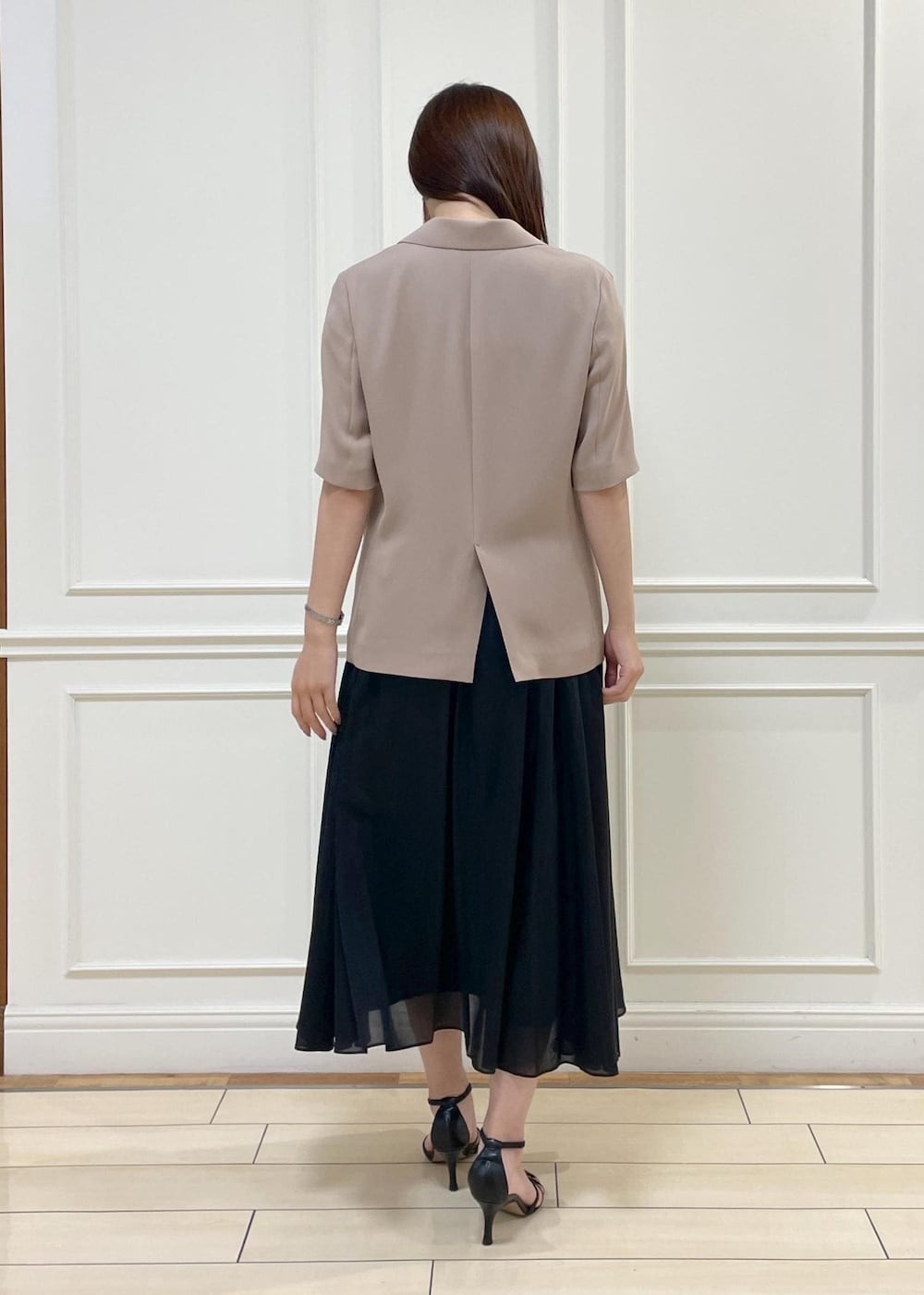 ブラウン系のトートバッグ、ベージュ系のテーラードジャケット、ブラック系のスカートを着用したレディースの夏コーディネートの4枚目の写真