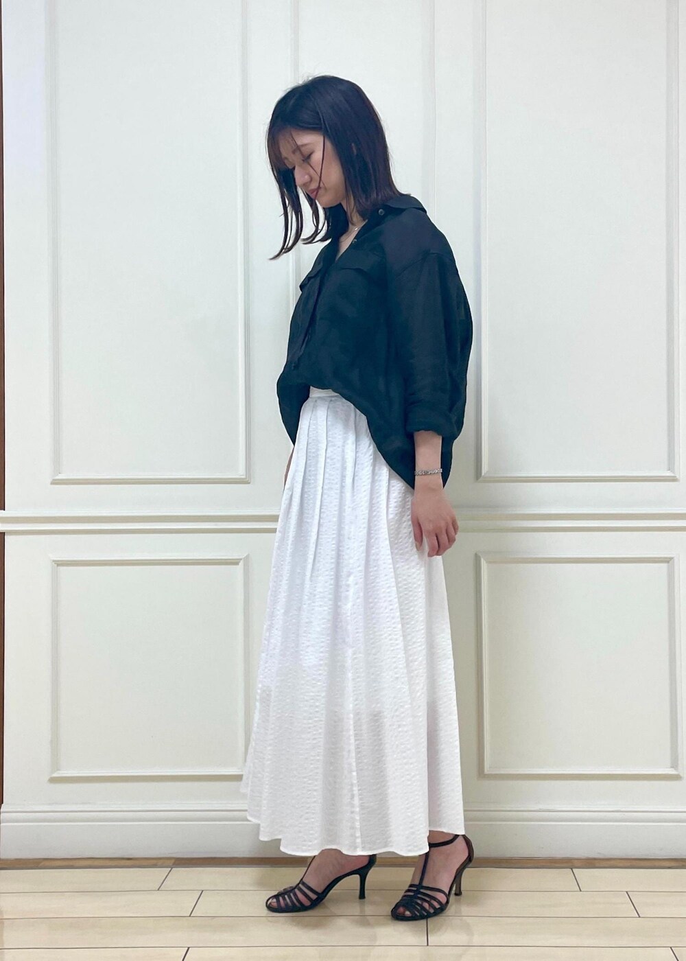 ブラック系のサンダル、ブラック系のシャツ/ブラウス、ホワイト系のスカートを着用したレディースの夏コーディネートの2枚目の写真