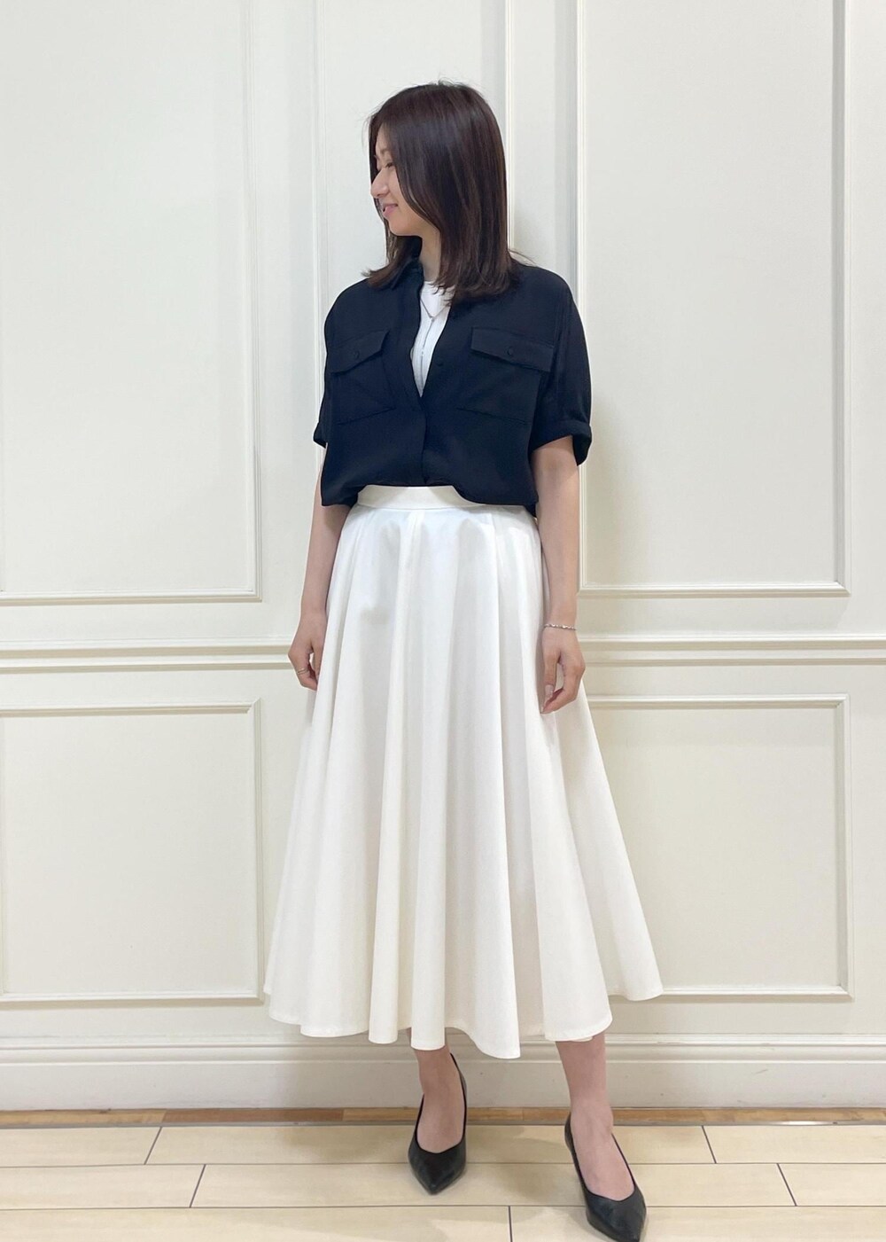 ブラック系のハンドバッグ、ホワイト系のスカート、ホワイト系のニット/セーターを着用したレディースの春コーディネートの10枚目の写真