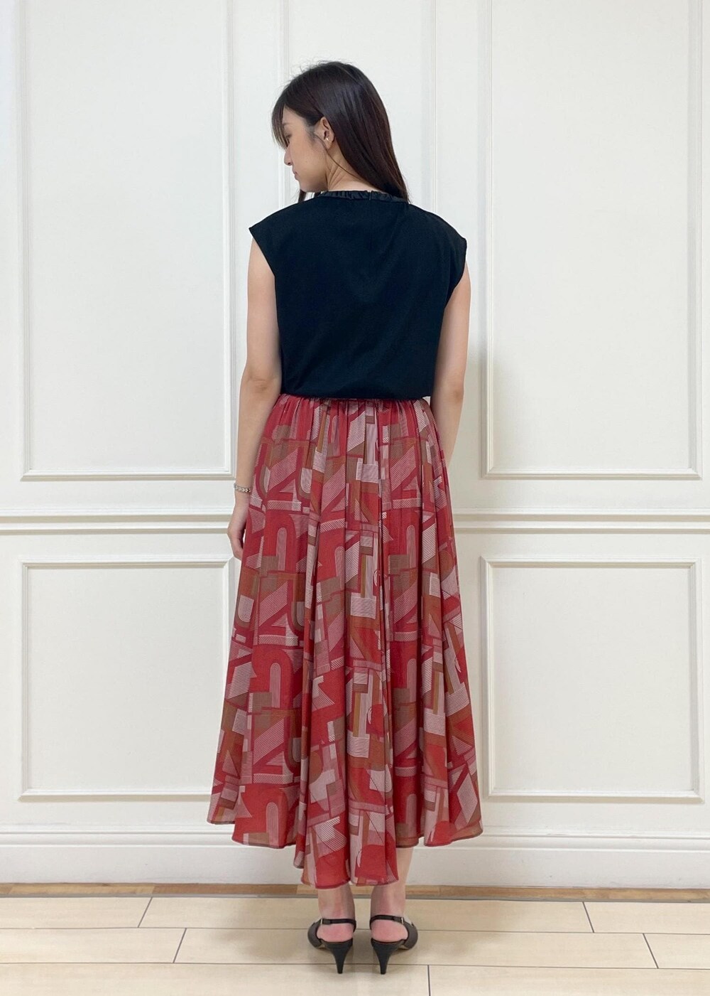 ブラック系のパンプス、レッド系のスカート、ブラック系のTシャツ/カットソーを着用したレディースの夏コーディネートの4枚目の写真