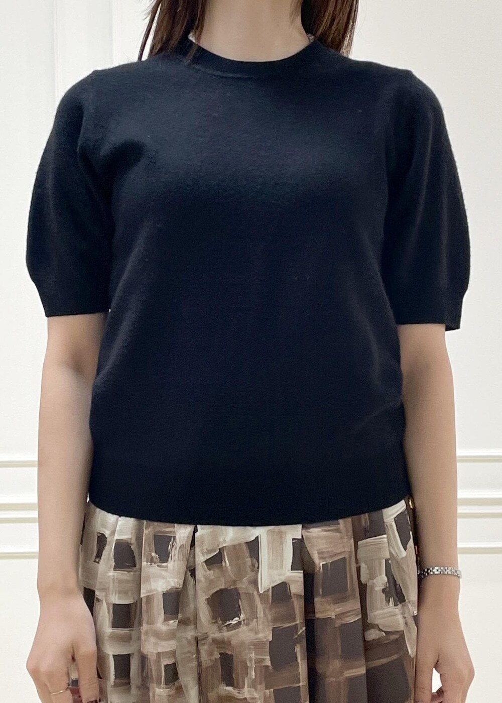 グレー系のハンドバッグ、ブラウン系のスカート、ブラック系のニット/セーターを着用したレディースの秋コーディネートの4枚目の写真