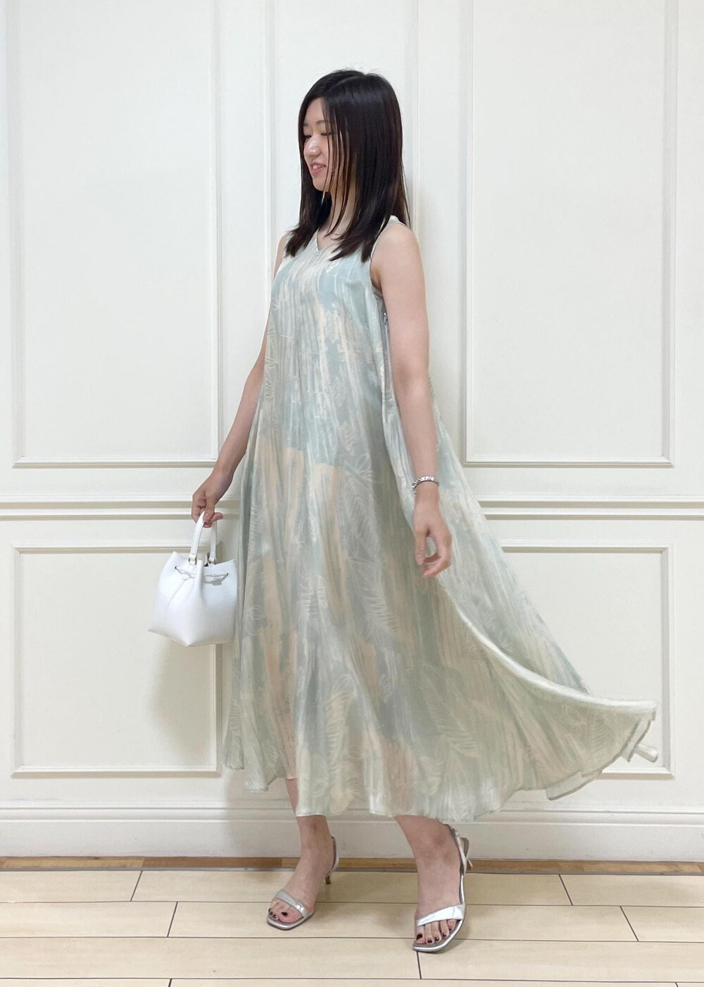 ホワイト系のハンドバッグ、シルバー系のサンダル、グリーン系のワンピースを着用したレディースの夏コーディネートの3枚目の写真