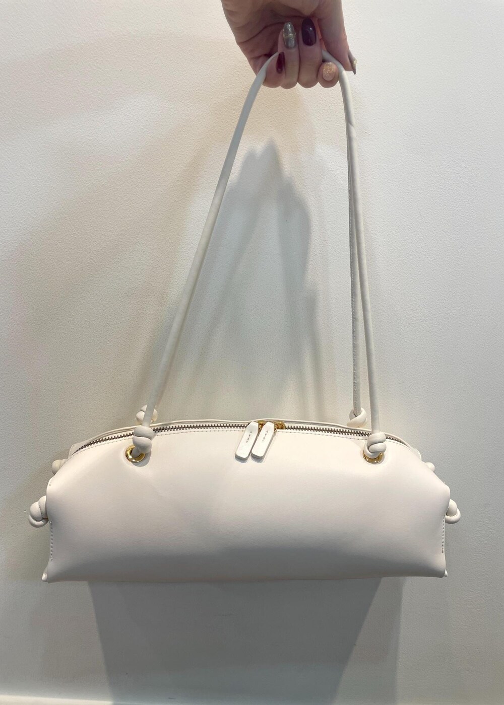 ブラック系のブーツ、ホワイト系のハンドバッグ、ブラック系のスカートを着用したレディースの秋コーディネートの7枚目の写真