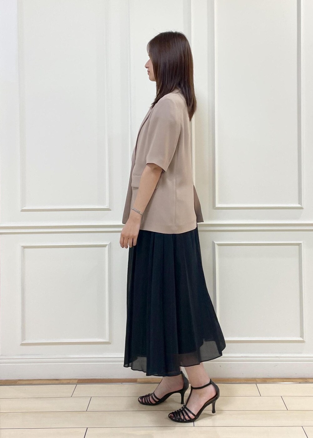 ブラウン系のトートバッグ、ベージュ系のテーラードジャケット、ブラック系のスカートを着用したレディースの夏コーディネートの3枚目の写真