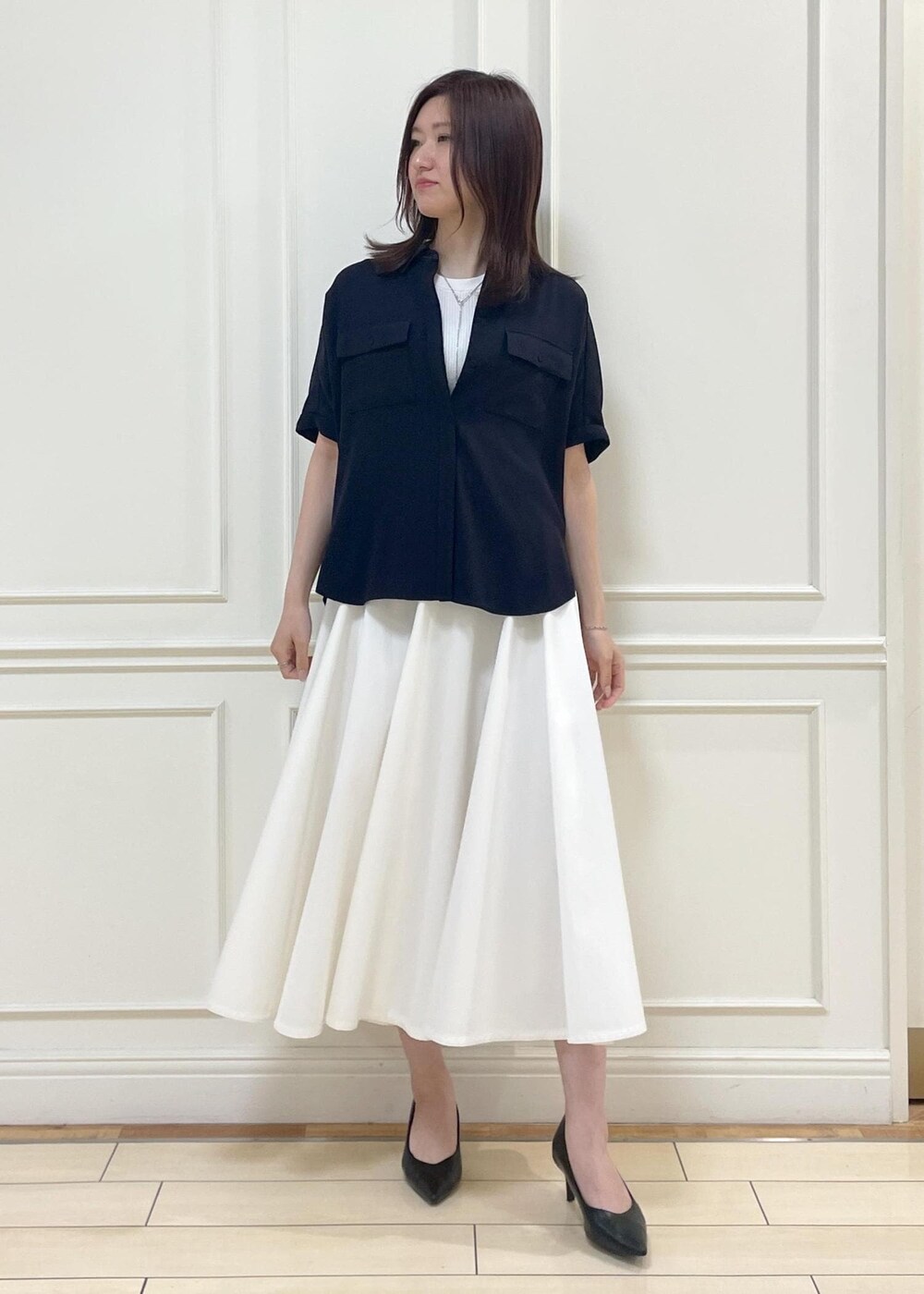 ブラック系のハンドバッグ、ホワイト系のスカート、ホワイト系のニット/セーターを着用したレディースの春コーディネートの2枚目の写真