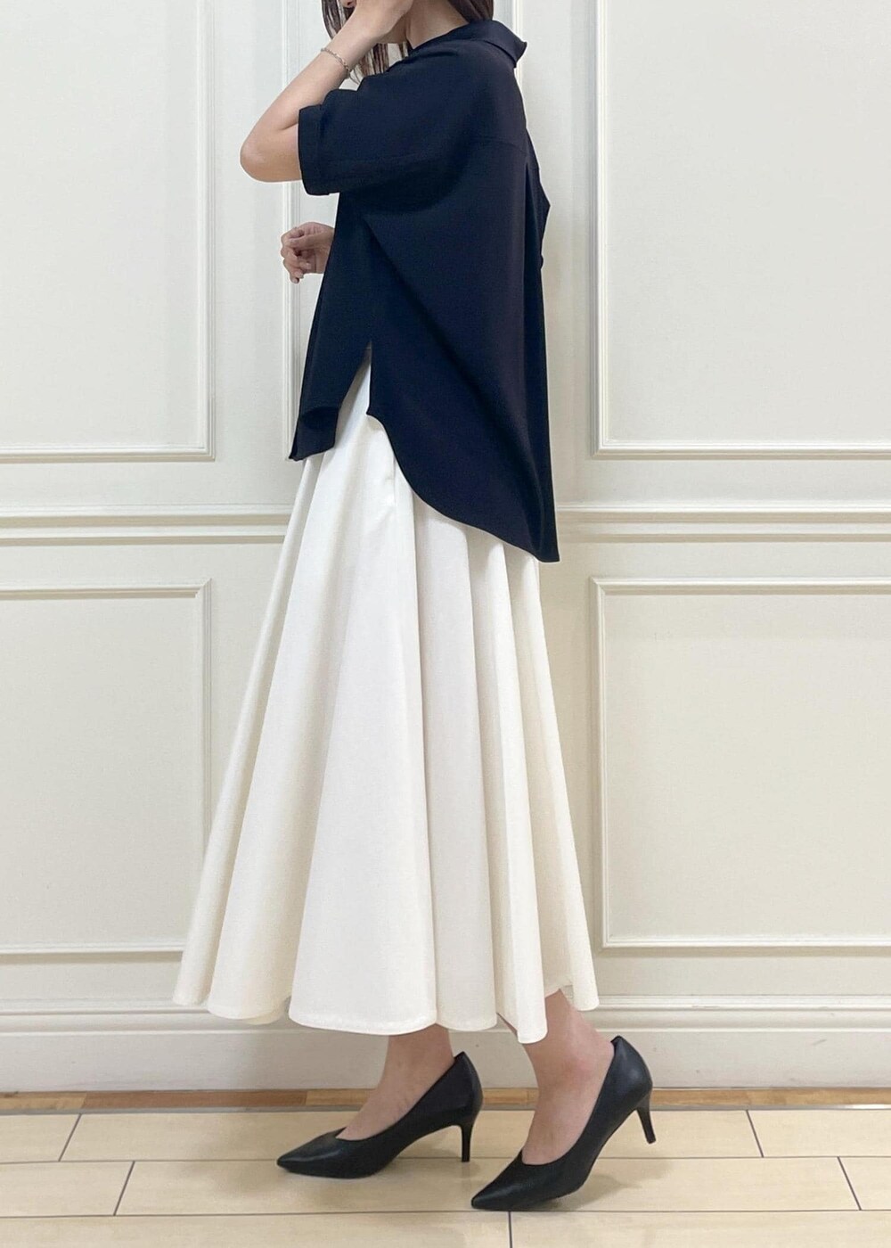 ブラック系のハンドバッグ、ホワイト系のスカート、ホワイト系のニット/セーターを着用したレディースの春コーディネートの3枚目の写真