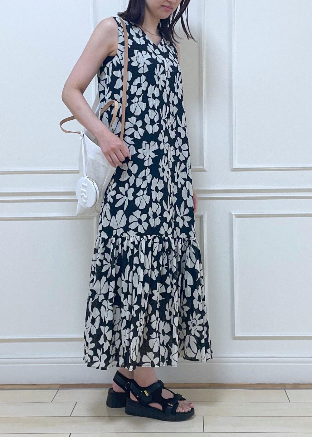 ブラック系のサンダル、ホワイト系のトートバッグ、ブラック系のワンピースを着用したレディースの夏コーディネートの2枚目の写真
