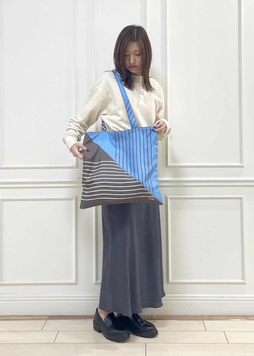 ブルー系のトートバッグ、グレー系のスカート、ベージュ系のスウェットを着用したレディースの秋コーディネートの8枚目の写真