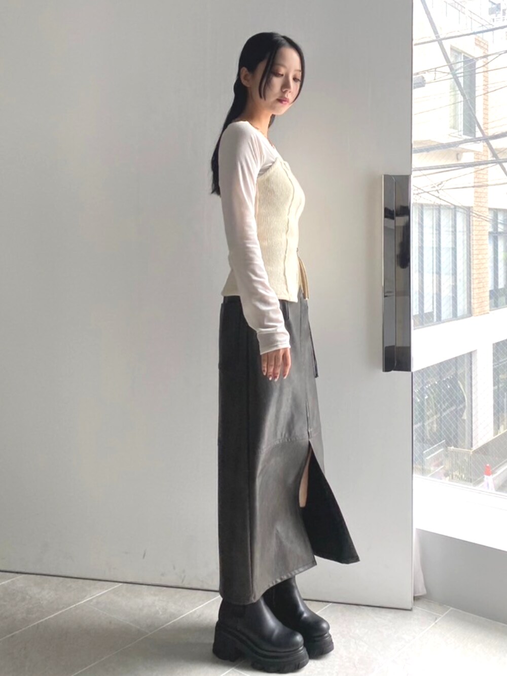 ブラック系のブーツ、ホワイト系のTシャツ/カットソー、グレー系のスカートを着用したレディースの秋コーディネートの3枚目の写真