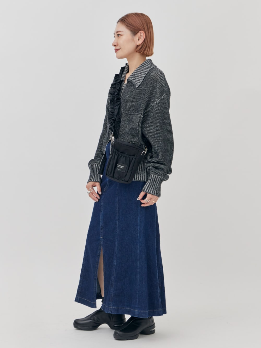 ブラック系のニット/セーター、ブラック系のショルダーバッグ、ブルー系のスカートを着用したレディースの秋コーディネートの2枚目の写真