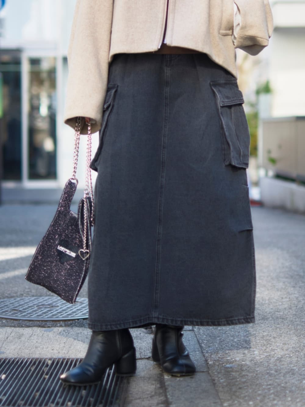 ブラック系のデニムスカート、ベージュ系のブルゾン、ブラック系のショルダーバッグを着用したレディースの冬コーディネートの4枚目の写真