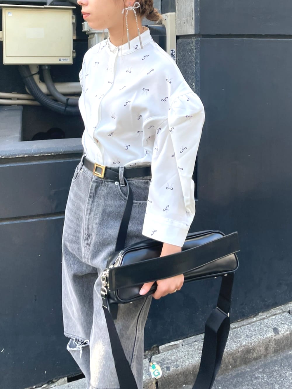 ブラック系のショルダーバッグ、ホワイト系のシャツ/ブラウス、ブルー系のデニムパンツを着用したレディースの秋コーディネートの3枚目の写真