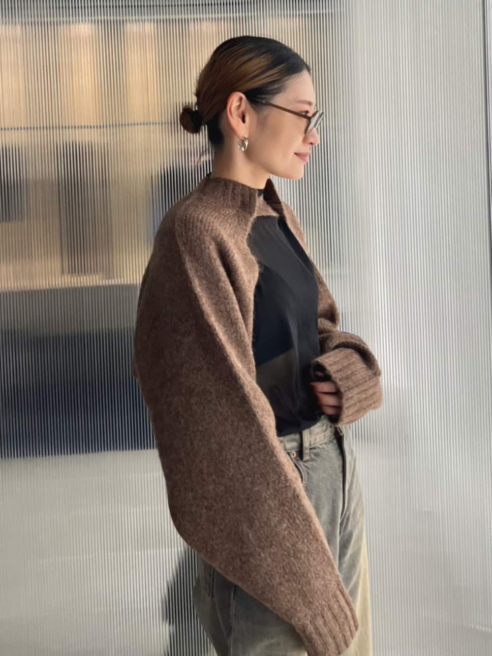 ブラック系のデニムパンツ、ベージュ系のスリッポン、ブラウン系のカーディガン/ボレロを着用したレディースの秋コーディネートの2枚目の写真